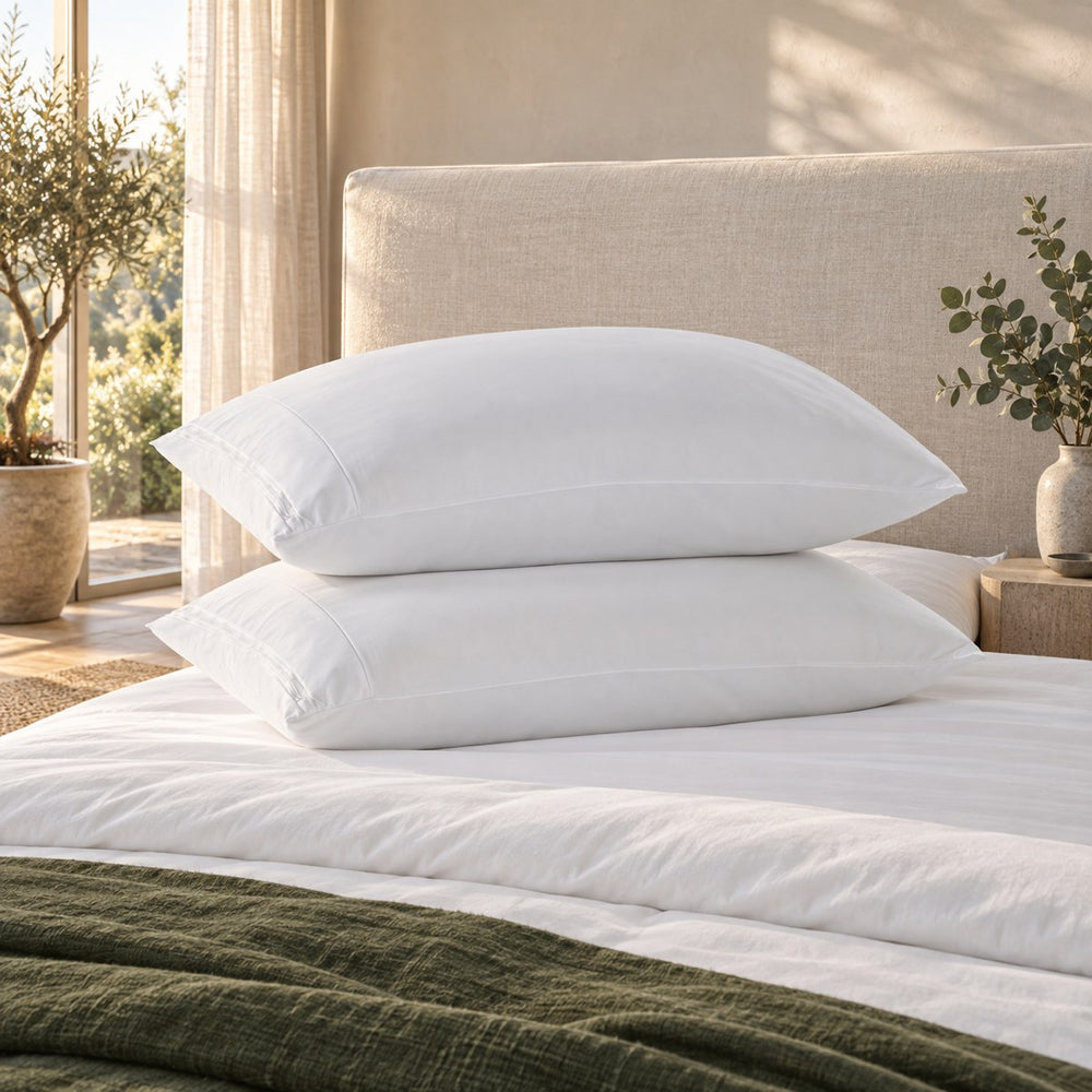 Two pillows in the Huxberry ActivChill Pillow Protector against an upholstered headboard
