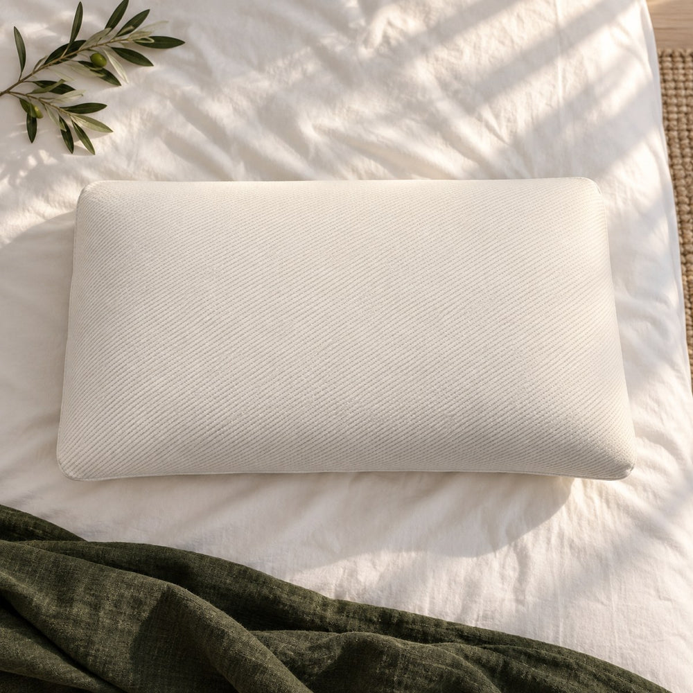 Huxberry Organic Latex Pillow from above on white cotton sheets with a green linen throw